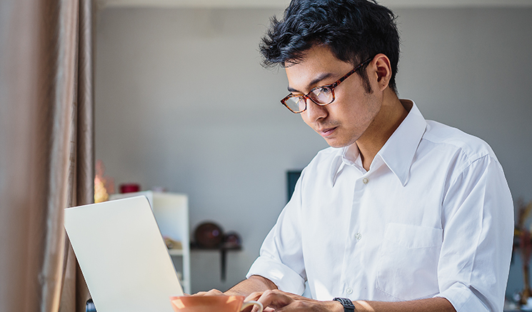 Young Asian business man working with laptop computer while sitting in coffee shop cafe